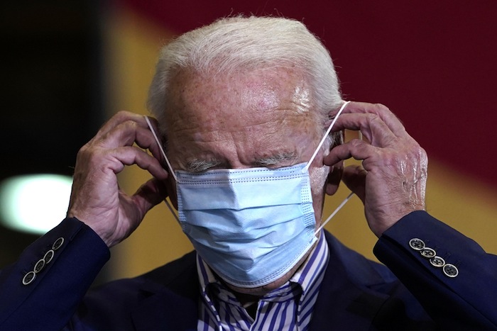 Joe Biden essaye de mettre son masque tout seul.